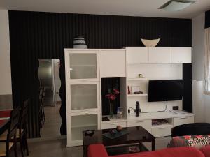 a living room with a tv and a white cabinet at Apartamentos Turísticos "El Jardín" in Teruel