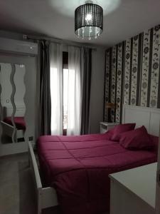 a bedroom with a purple bed and a chandelier at Casa cueva de la sombra in Setenil +15 photos