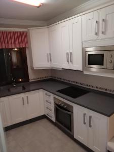 a kitchen with white cabinets and a black counter top at Casa cueva de la sombra in Setenil