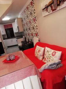 a small room with a red couch and a kitchen at Casa cueva de la sombra in Setenil