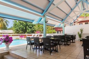 a patio with tables and chairs and a swimming pool at The Originals City, Hôtel Belova, Cayenne Sud (Inter-Hotel) in Montjoly