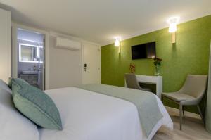 a bedroom with a white bed and a green wall at Ver Belém Suites in Lisbon