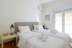 2 białe łóżka w pokoju z oknem w obiekcie Athens Heartbeat w Atenach