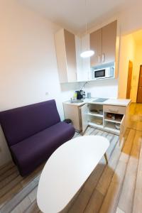 a living room with a purple couch and a kitchen at Garsoniere Central in Satu Mare
