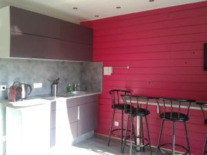 シャンベリにあるChalet Insoliteのピンクの壁とバースツール付きのキッチン