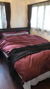 ein großes Bett in einem Schlafzimmer mit zwei Fenstern in der Unterkunft Guest House "Ro"kumano in Shimonoseki