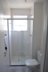 a white bathroom with a shower and a toilet at Espaço Mahina - Unidade Dez - Apartamento para temporada Praia Grande Ocian in Praia Grande