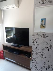 sala de estar con TV de pantalla plana en la pared en Flat Jardins do Atlântico, frente mar, en João Pessoa