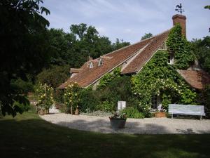 ein mit Efeu bedecktes Haus mit einer Bank davor in der Unterkunft Les Sapins in Vitry-aux-Loges