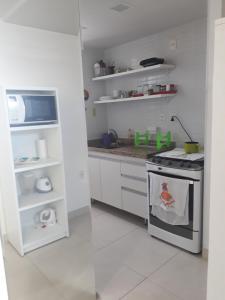 cocina blanca con fogones y encimera en Flat Jardins do Atlântico, frente mar, en João Pessoa