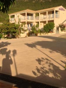 a shadow of a street light in front of a building at Hôtel Camparellu in Galeria