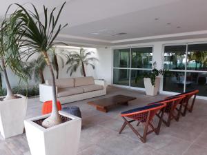uma sala de estar com um sofá e palmeiras em Flat Jardins do Atlântico, frente mar em João Pessoa