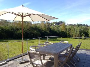 una mesa de madera y sillas con sombrilla en De Waterkriek, en Borgloon