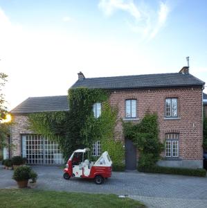 einem roten Truck, der vor einem Backsteinhaus parkt in der Unterkunft De Waterkriek in Borgloon