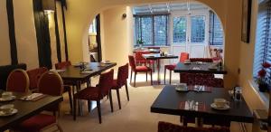 a restaurant with tables and red chairs and windows at The Tudor Hotel in Harrow