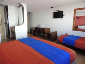 Habitación de hotel con 2 camas, escritorio y TV. en Hotel Kyoto, en Puebla