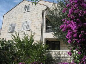 un edificio de ladrillo blanco con ventanas y flores púrpuras en Apartments and Rooms Artemida, en Dubrovnik