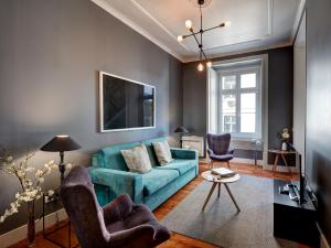 - un salon avec un canapé bleu et deux chaises dans l'établissement Lisbon Canaan Boutique Apartments Fanqueiros 114 by Get Your Stay, à Lisbonne