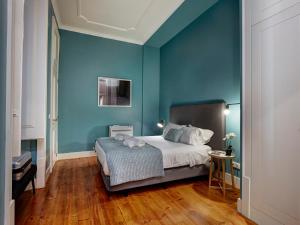 リスボンにあるLisbon Canaan Boutique Apartments Fanqueiros 114 by Get Your Stayの青い壁のベッドルーム1室、ベッド1台、テーブルが備わります。