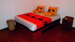 a bed with orange pillows and a red blanket at Luck Uyana Cabana Pinnawala in Pinnawala