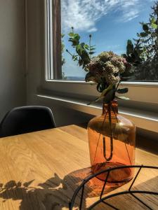 eine Vase mit Blumen auf einem Tisch vor einem Fenster in der Unterkunft Stylový apartmán přímo u lanovky, vlastní garážové stání in Janské Lázně