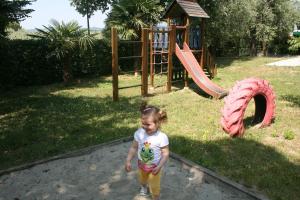 a little girl walking in front of a playground at Residence Miralago Rooms & Apartments in Manerba del Garda