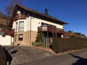 Una gran casa blanca con balcones de madera. en Ferienwohnung am Weinberg - Altenahr / Ahrtal en Altenahr