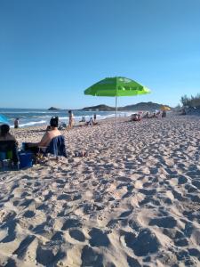 een strand met een groene parasol en mensen erop bij Pousada Boto Mar in Garopaba