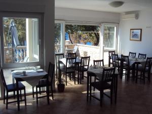 un comedor con mesas, sillas y ventanas en Villa Kanata, en Povile