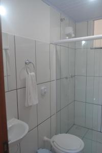 Baño blanco con aseo y lavamanos en Suítes Centro, en Arraial do Cabo