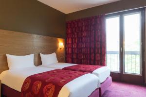 a hotel room with two beds and a window at Hôtel Tour Maje in Rodez
