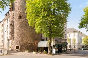 un edificio de ladrillo alto con un árbol delante de él en Hôtel Tour Maje en Rodez