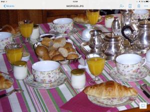 una mesa con tazas y platos de comida y pan en Les Sapins, en Vitry-aux-Loges