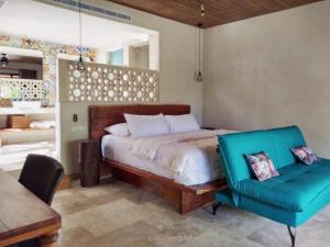1 dormitorio con 1 cama y 1 silla azul en Azucar Hotel Tulum, en Tulum