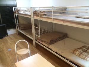 two bunk beds in a room with a table and a chair at Shinjuku Hostel in Tokyo