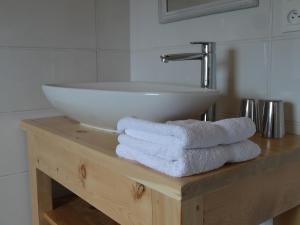 a bathroom with a sink and towels on a wooden table at Maison d'hôtes l'Arnica in La Bréole