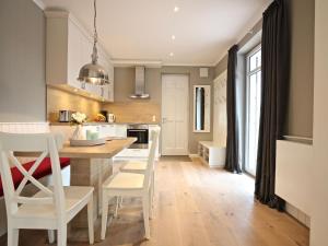 eine Küche mit weißen Stühlen und einem Holztisch in der Unterkunft Kleine Charlotte - Traumwohnung mit Terrasse für 4 Personen in Wangerooge