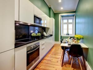 a kitchen with green walls and a table with chairs at Lisbon Canaan Boutique Apartments Gaivotas by Get Your Stay in Lisbon