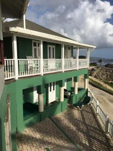 a green house with a balcony and the ocean at The Atlantis Historic Inn in Saint Joseph