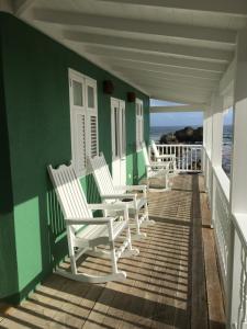 a row of chairs sitting on a porch overlooking the ocean at The Atlantis Historic Inn in Saint Joseph