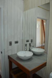 Hotel Nueve Ríos في فالديفيا: حمام مع مغسلتين على منضدة مع مرآة