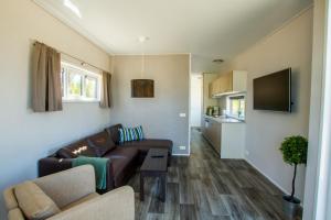 a living room with a brown couch and a kitchen at Sveastranda Camping in Gullor