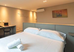 a bedroom with two beds and a desk with a laptop at Íbis Styles Itaúna in Itaúna