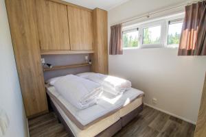 a bedroom with a bed with white sheets and a window at Sveastranda Camping in Gullor