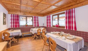 a restaurant with tables and chairs and red and white curtains at LEOPOLDINE Apart Zimmer in Längenfeld
