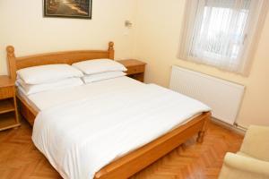 - une chambre avec un grand lit et des draps blancs dans l'établissement B&B Passage, à Sremska Mitrovica