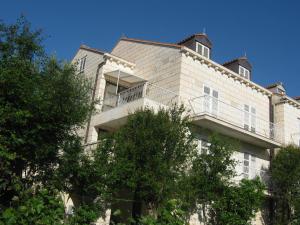 een groot wit gebouw met bomen ervoor bij Apartments and Rooms Artemida in Dubrovnik