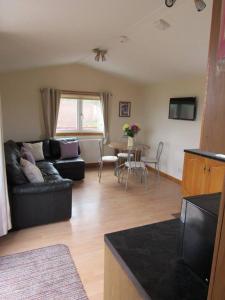 a living room with a black couch and a table at Golden Oak Chalet in Dunbar