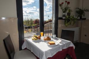 a table with two plates of food and a glass of wine at Hotel Puerta de la Santa in Ávila