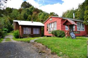 a red house with a sign in front of it at Tranqueras del Monte in Chaitén